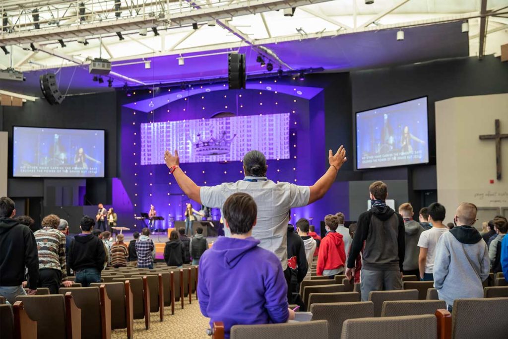 image of man holding hands up in prayer at a performance