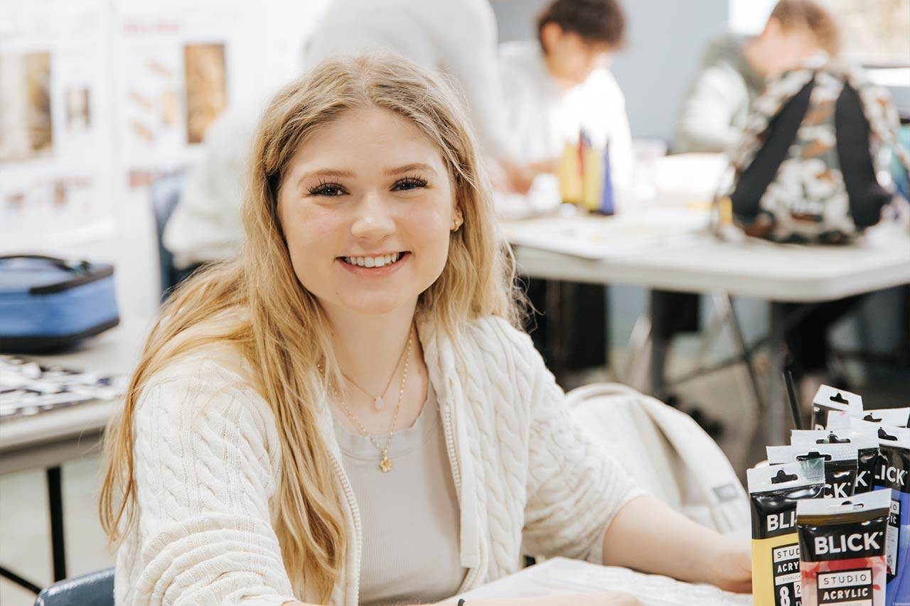 image of a young female student smiling in acrylics class