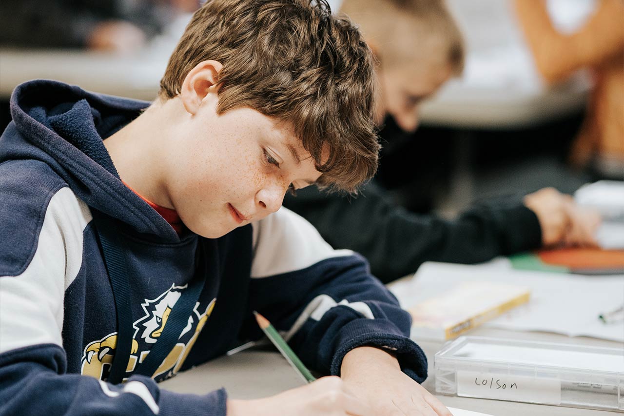 image of a young male student erasing a mistake on his paper