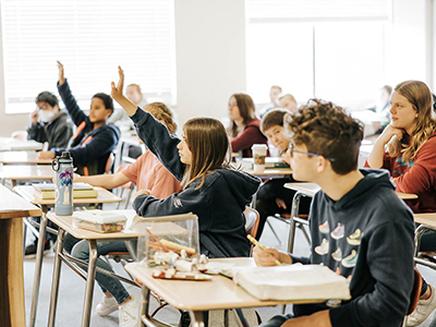 students raising hands in class