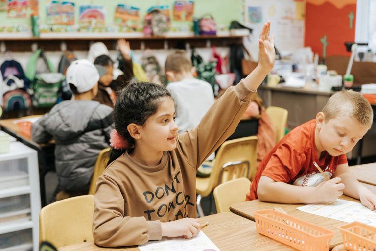 girl in classroom raising her hand